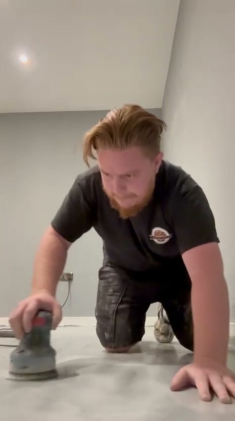 Luke preparing a floor with a hand-held sander