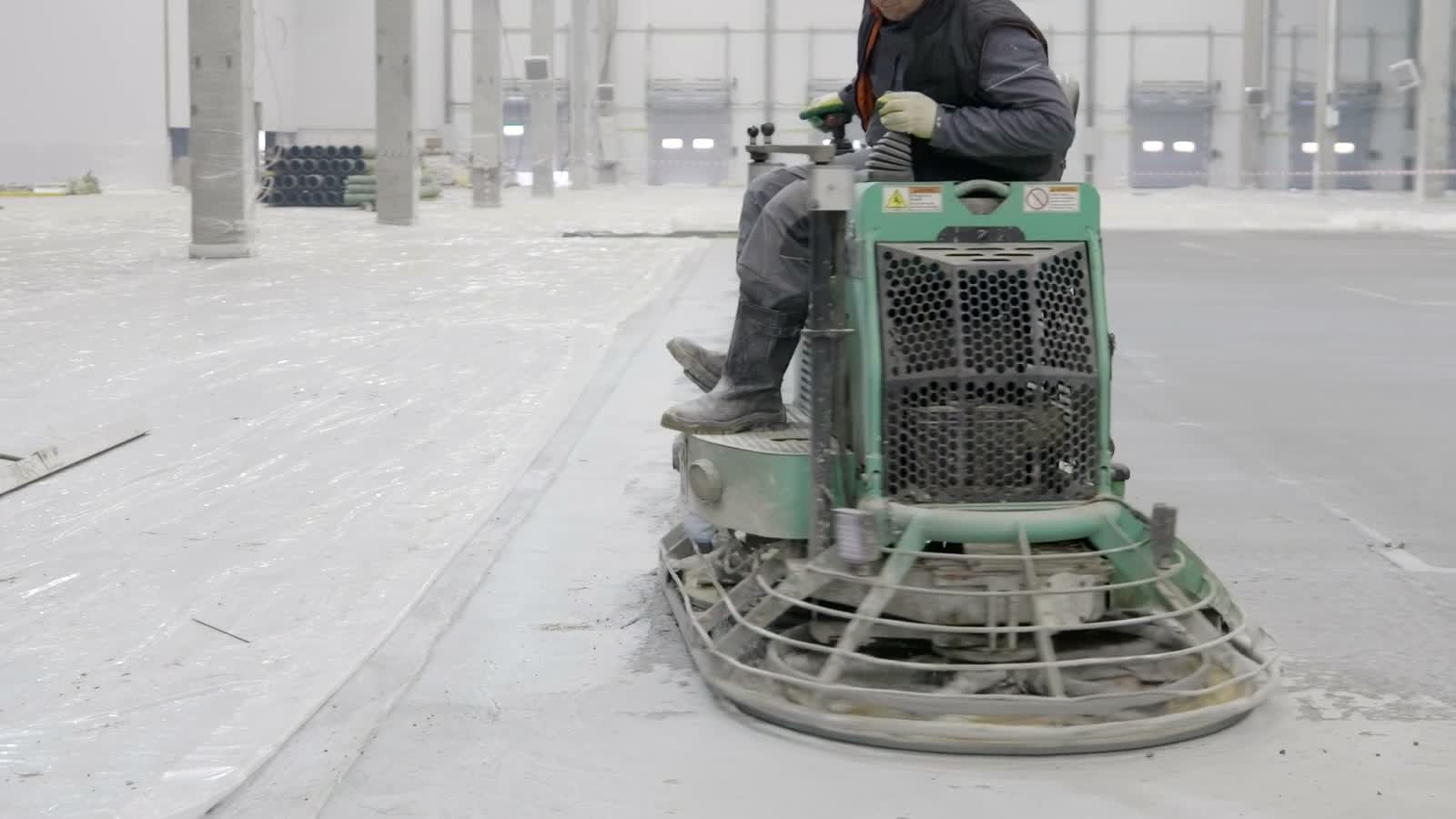 A concrete finishing machine working across a large indoor floor