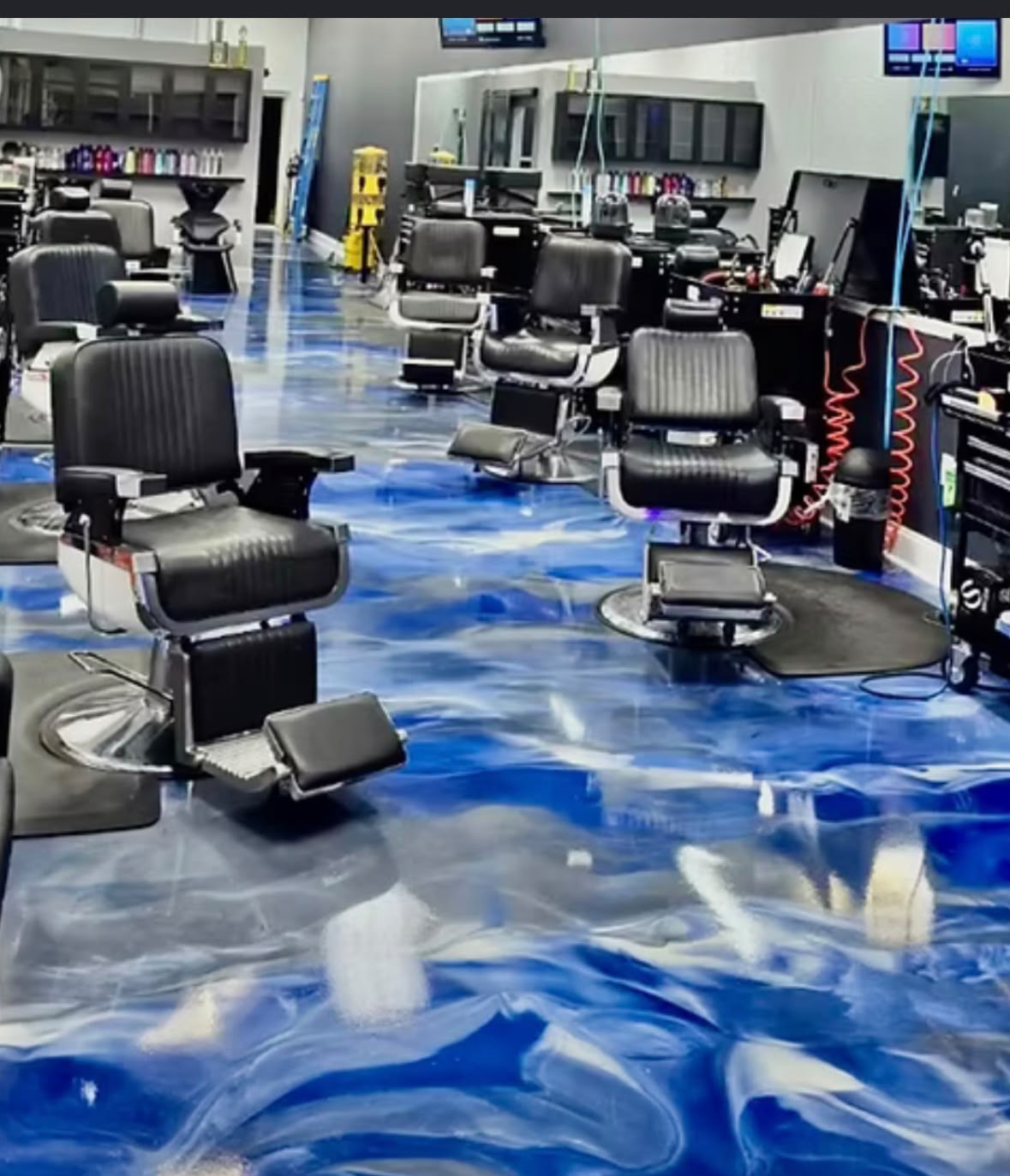 Blue, silver and white metallic flooring through a barbershop with black chairs
